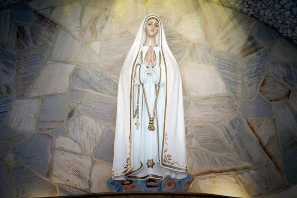 Estatua de madera blanca de la Virgen con manos juntas en oración